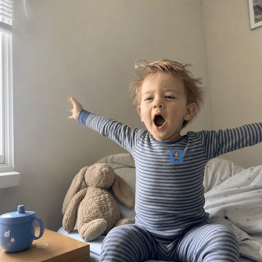 Child sleeping peacefully with a StuffyPatch sticker on their pajama collar.