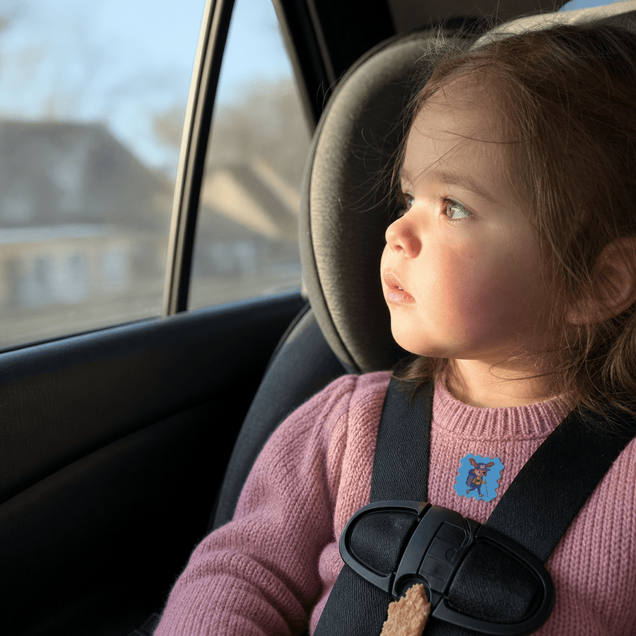 A parent tucking a sleeping child into bed on a trip, a StuffyPatch sticker on their pajama collar.