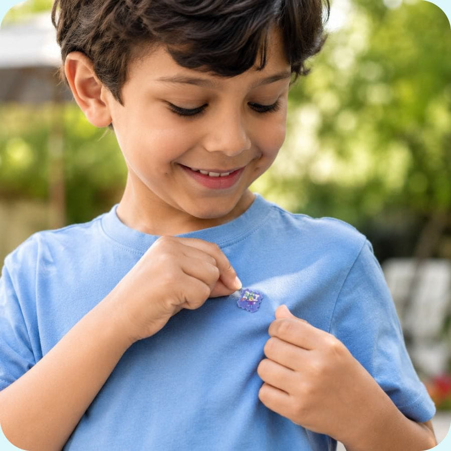 A child wearing BuzzPatch mosquito repellent stickers on their clothing while playing outdoors.