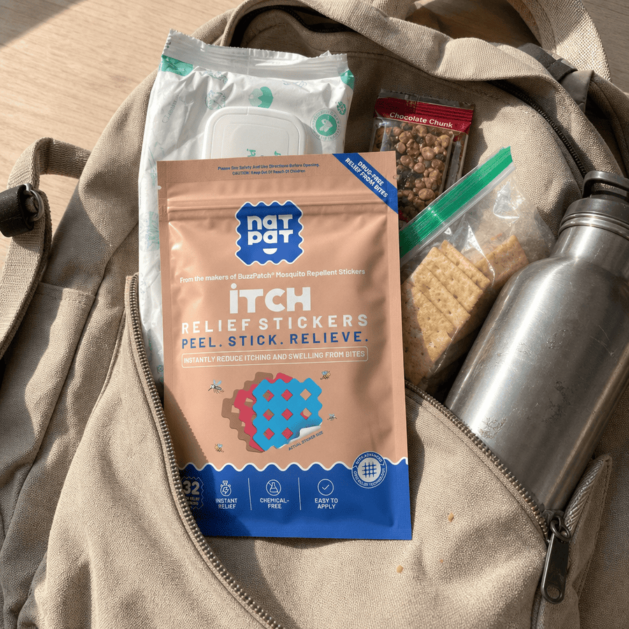 A NatPat Itch Relief Stickers pack tucked into a backpack pocket next to snacks and a stainless steel water bottle.