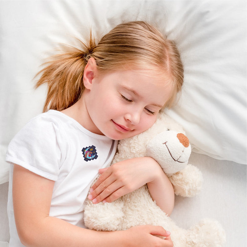 Girl sleeping peacefully with a SleepyPatch sticker on her shirt, hugging a teddy bear