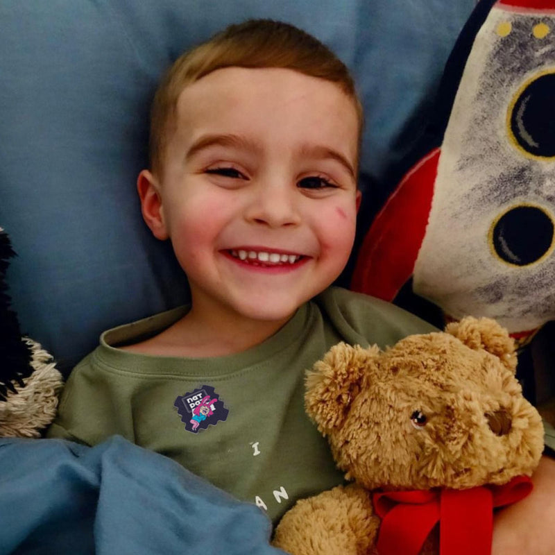 Smiling boy in bed wearing a SleepyPatch sticker