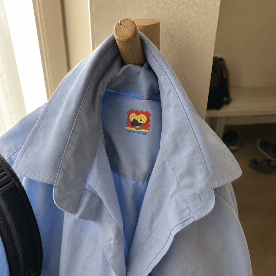 A school shirt hanging on a hook with the Seasonal sticker patch attached to the inside collar.