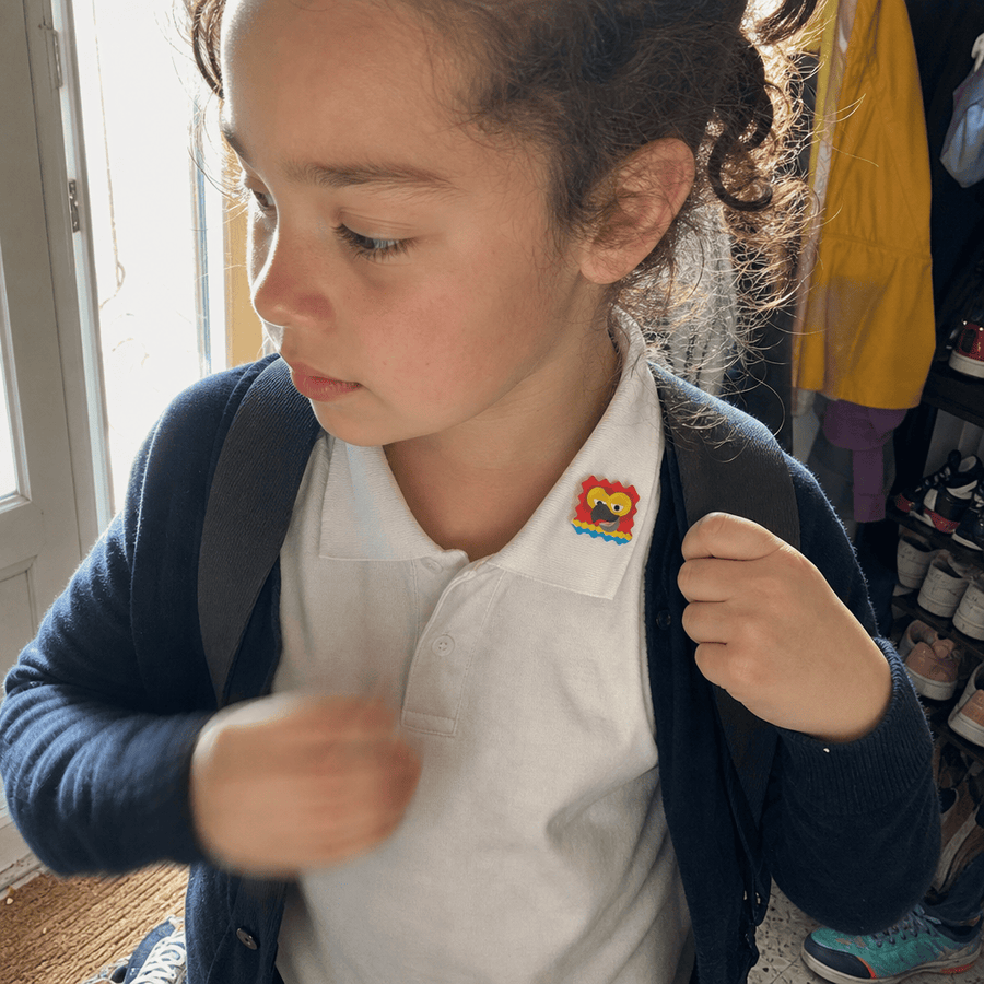 A child wearing a backpack with a Seasonal allergy patch stuck to their shirt collar.
