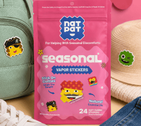 A pink pouch of Seasonal vapor stickers surrounded by a backpack, sun hat and denim, styled with a cartoon monster mascot.