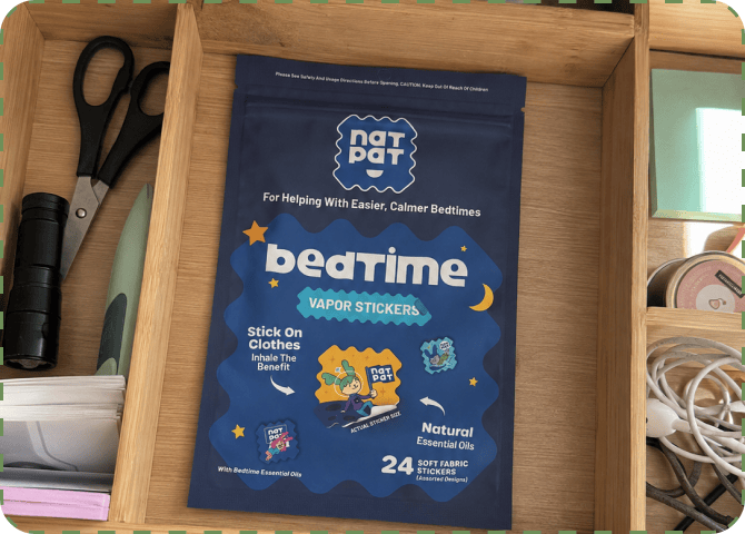 A single navy NATPAT bedtime Vapor Stickers pouch lying in an open wooden desk drawer alongside scissors, a black torch, notepads and coiled cables.