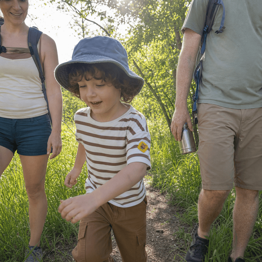 A child playing outdoors in long grass with a TrailPatch sticker on their shirt.