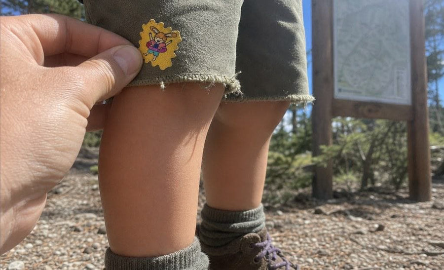A family at a campsite in the woods, kids wearing TrailPatch stickers on their shirts.