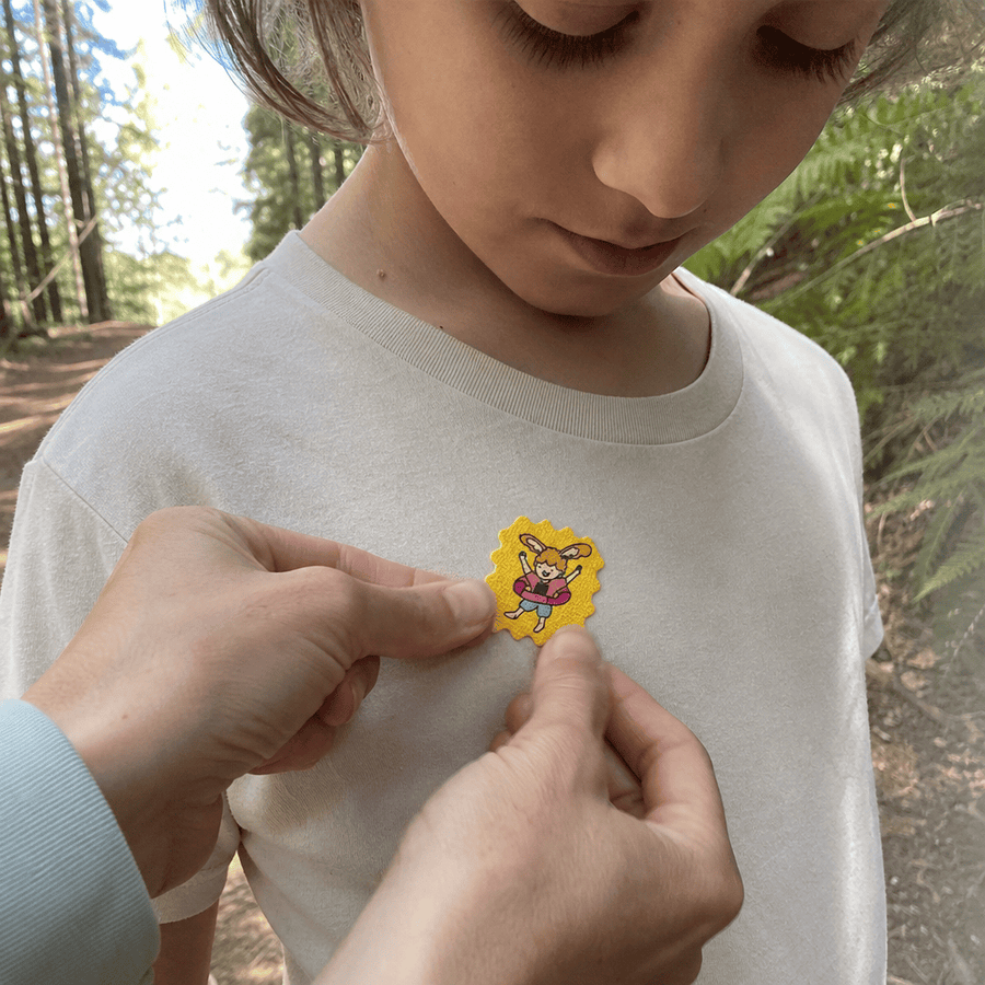 A parent pressing a TrailPatch sticker onto a child's sleeve, nothing touching the skin.
