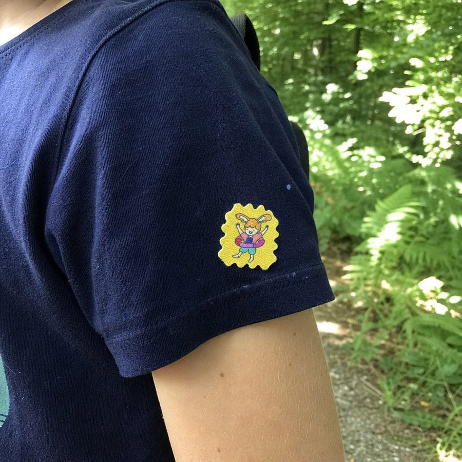 Parent and child on a forest trail, a TrailPatch sticker on the child's shirt.