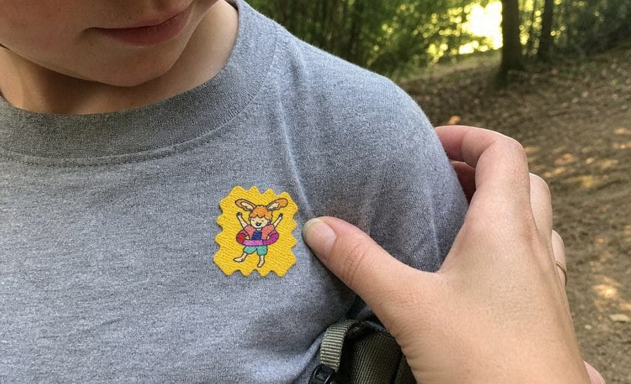 A family at a campsite in the woods, kids wearing TrailPatch stickers on their shirts.