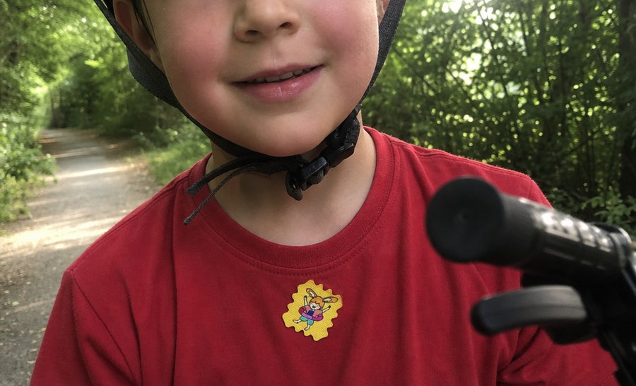 A family at a campsite in the woods, kids wearing TrailPatch stickers on their shirts.