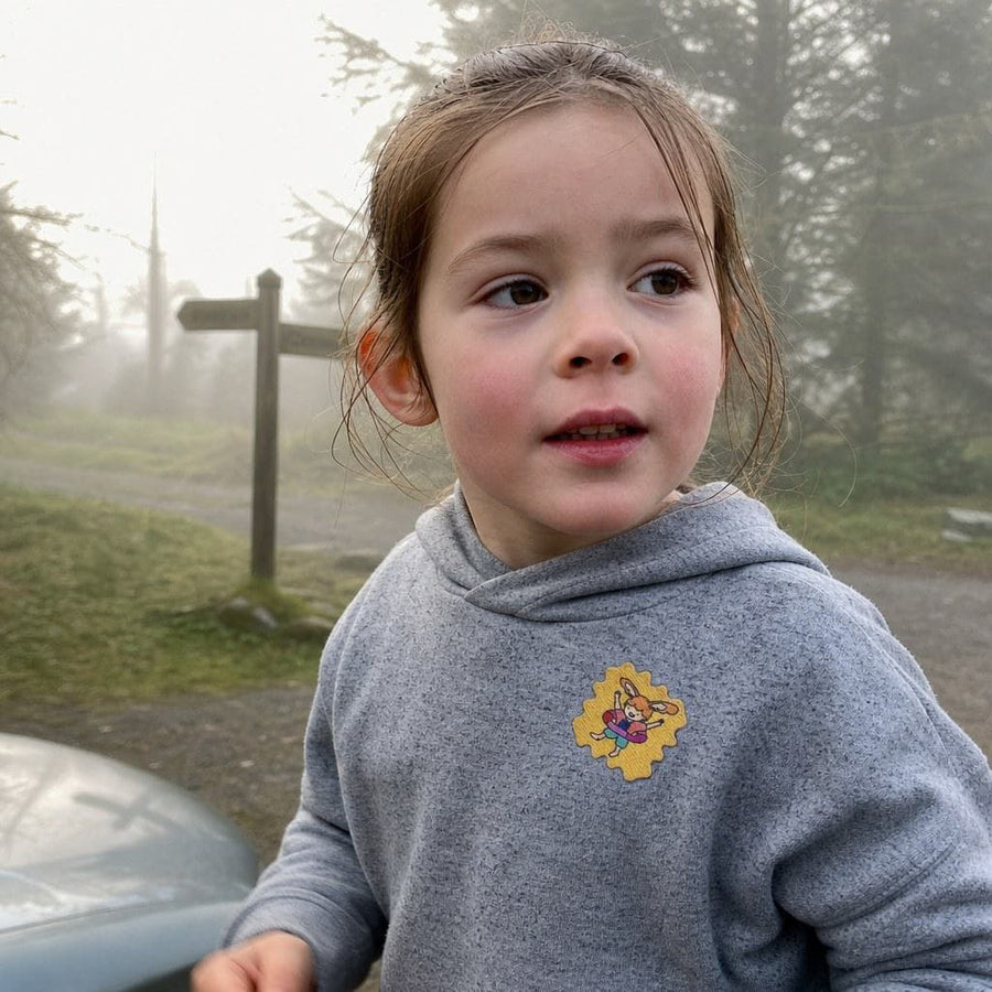 Parent and child on a forest trail, a TrailPatch sticker on the child's shirt.