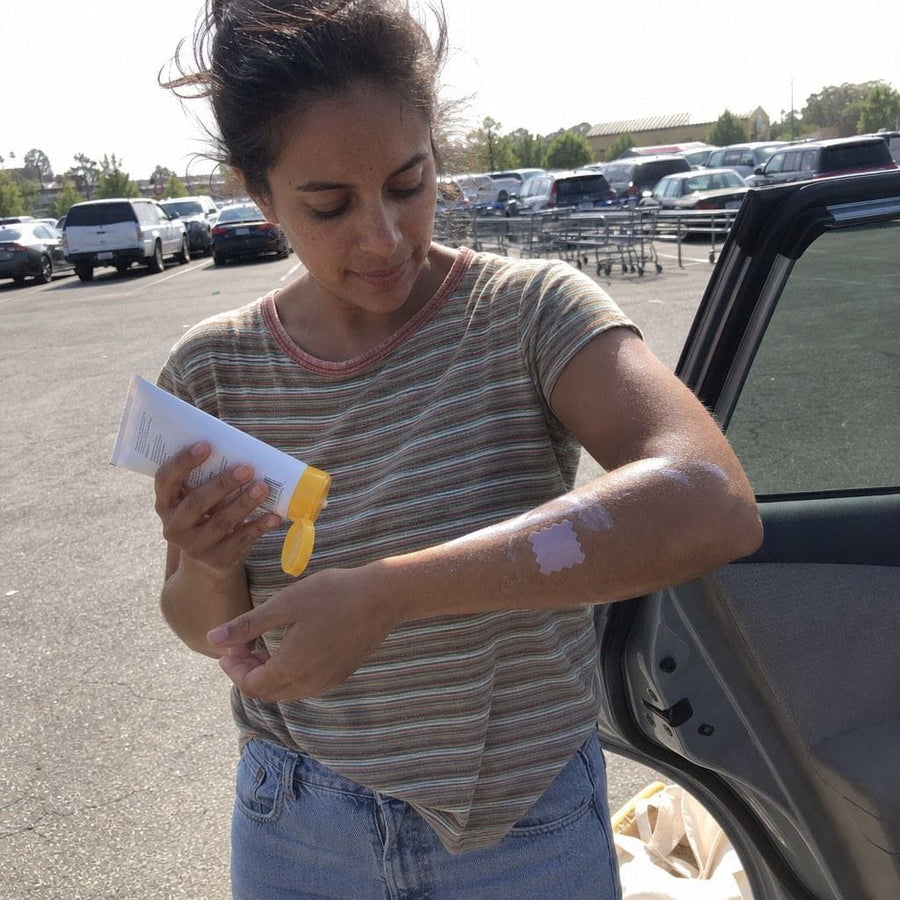 Adult forearm on a car roof, patch mid-turn to purple, keys in hand. Everyday sun, not beach glamour.