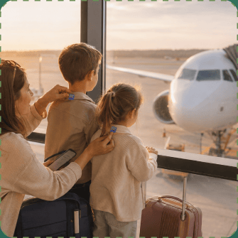 A mother at an airport gate window presses small blue ZenPatch stickers onto her son's jacket and her daughter's cardigan as the three of them watch a parked plane in golden evening light, suitcases at their feet.